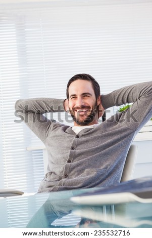Relaxed casual businessman leaning back at his desk in the office