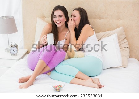Pretty friends having coffee on bed at home in the bedroom