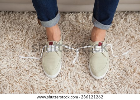 Casual mans shoelaces tied together at home in the living room