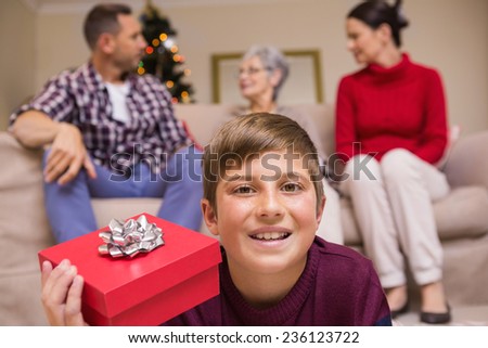 Smiling son with gift in front of his family at home in living room