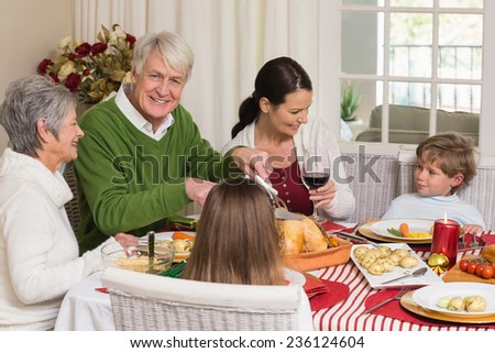 Happy grandfather carving chicken during christmas dinner at home in the living room