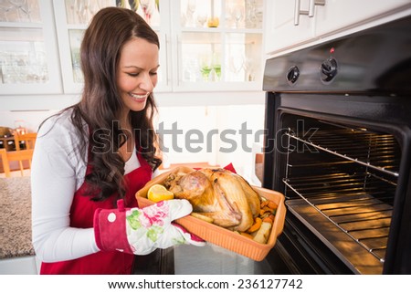 Smiling woman taking out her roast turkey at home in the kitchen