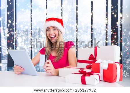 Festive blonde shopping online with tablet against glittering lights in room