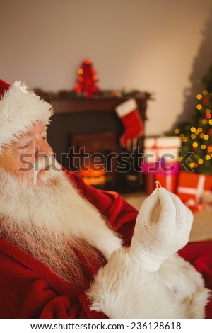 Father christmas holding engagement ring at home in the living room
