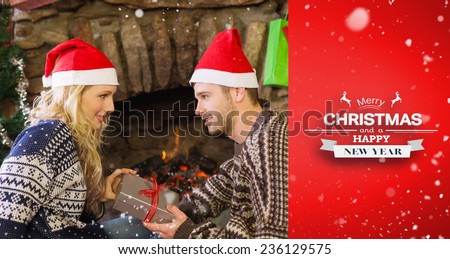 Man gifting woman in front of lit fireplace during Christmas against red vignette