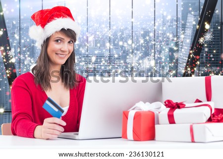 Festive brunette shopping online with laptop against glittering lights in room
