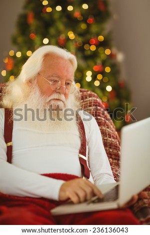 Father christmas typing on laptop at home in the living room