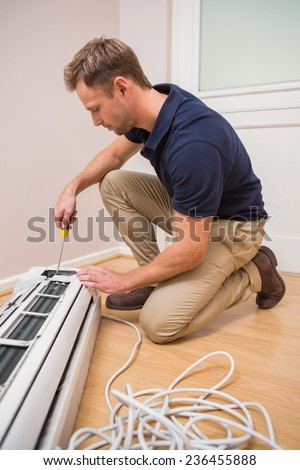 Focused handyman fixing air conditioning in a new house