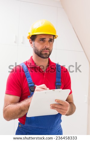 Construction worker taking notes on clipboard in a new house
