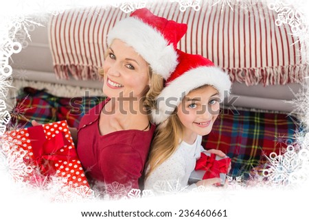 Festive mother and daughter smiling at camera with gifts against frost frame