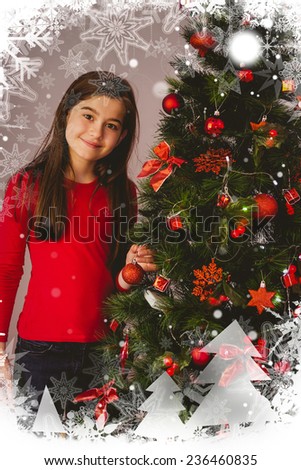 Little girl smiling at camera beside christmas tree against christmas theme frame in silver
