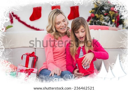 Little girl opening a gift at christmas with mother against frost frame