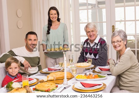 Woman holding christmas dinner with family at dinning table at home in the living room