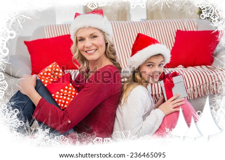 Festive mother and daughter smiling at camera with gifts against frost frame