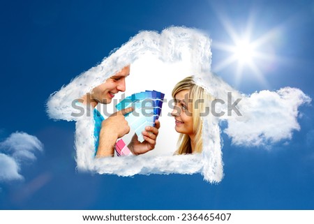 Cute couple chosing colours for painting house against bright blue sky with clouds