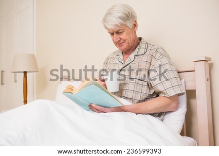 Senior man reading a book in bed at home in bedroom