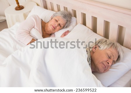 Senior couple sleeping in bed at home in the bedroom