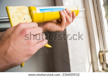Hands putting filling between window and wall in the kitchen