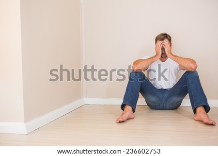 Depressed man sitting on floor in an empty room