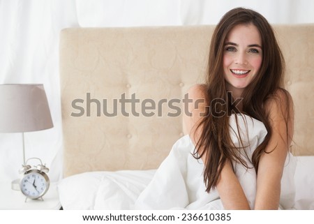 Pretty brunette waking up in bed at home in the bedroom