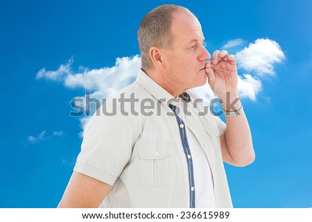 Older man holding hand to mouth for silence against cloudy sky