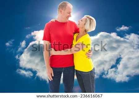 Happy mature couple hugging and smiling against blue sky with clouds and sun