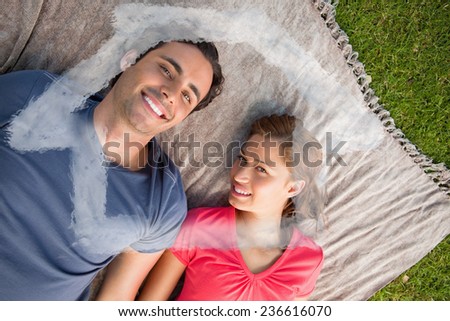 Two friends looking towards the sky while lying on a quilt against house outline in clouds