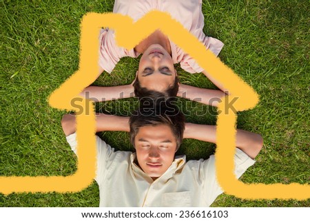 Woman and a man lying head to head with both hands behind their neck against house outline
