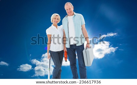 Happy older couple holding diy tools against cloudy sky with sunshine