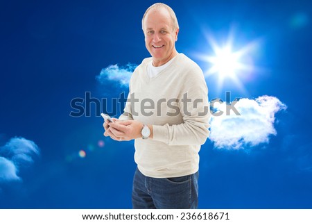 Happy mature man sending a text against bright blue sky with clouds