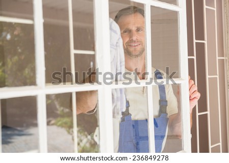 Handyman cleaning the window and smiling in a new house