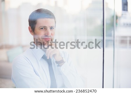 Smiling businessman looking out the window in his office