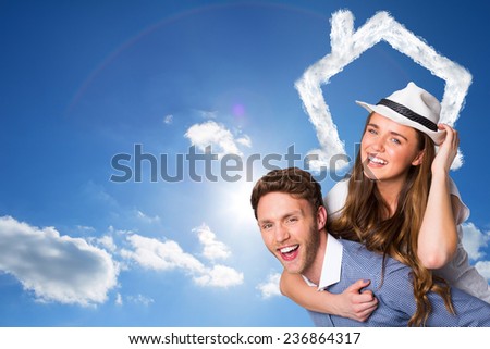 Smiling young man carrying woman against cloudy sky with sunshine