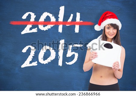 Festive fit brunette holding a weighing scales against blue chalkboard