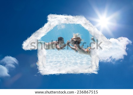 Cute couple kissing underwater in the swimming pool against bright blue sky with clouds