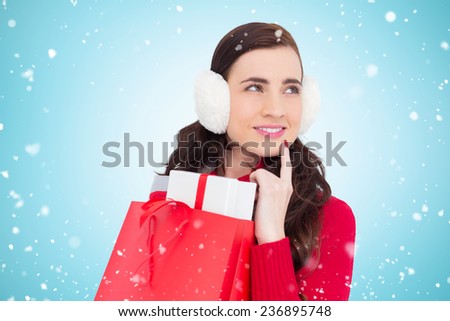 Brunette with ear muffs holding shopping bag full of gifts against blue vignette