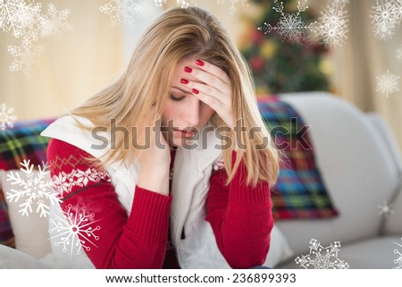Sad woman sitting in the living room on a couch against snowflakes