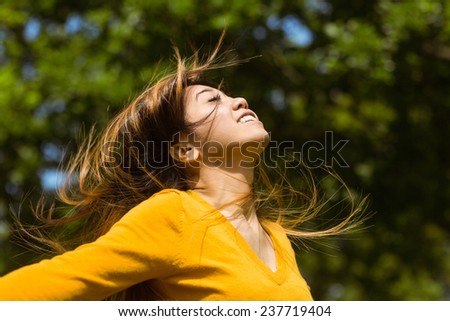 Side view of beautiful young woman with arms outstretched in the park