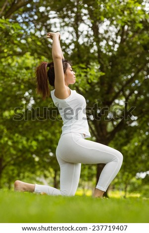 Side view of healthy and beautiful young woman with joined hands over head at park