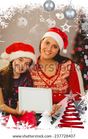 Festive mother and daughter showing tablet screen against christmas themed frame with decoration