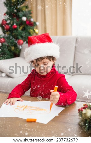 Festive little boy writing wish list against snow falling