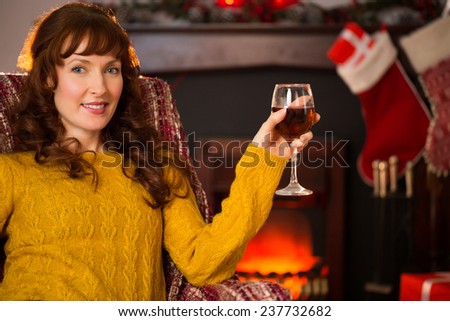 Woman sitting on a couch while holding a glass of red wine at christmas at home in the living room