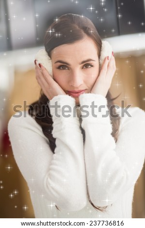 Pretty brunette with ear muffs against twinkling stars