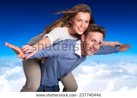 Smiling young man carrying woman against blue sky over clouds