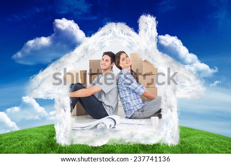 Couple sitting back-to-back against green field under blue sky