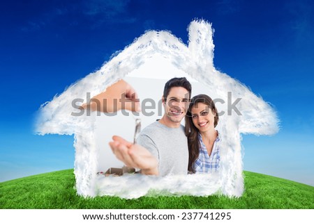 Happy man being given a house key against green hill under blue sky