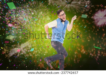 Geeky hipster dancing and smiling against colourful fireworks exploding on black background