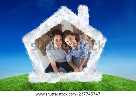 Overview of a man and his wife holding house plans against green hill under blue sky