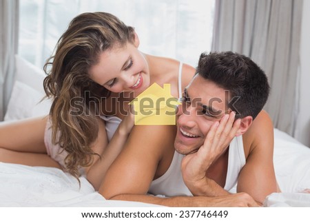 Romantic young couple in bed at home against house outline