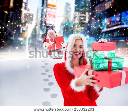 Festive blonde holding pile of gifts against santa delivering gifts in city